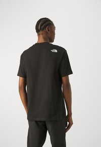 Zwarte katoenen t-shirt met een ronde hals en korte mouwen. Opmerkelijk wit logo op de bovenrug. Soepele textuur.