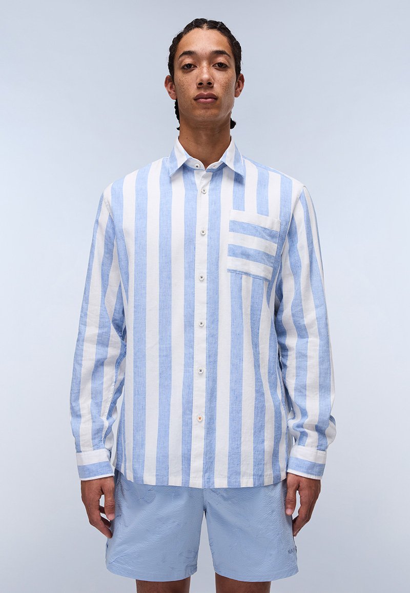 Camisa de botones de manga larga a rayas azul claro y blanca con un bolsillo en el pecho, hecha de una tela texturizada, combinada con pantalones cortos azul claro.