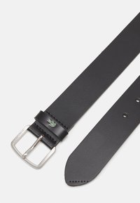 Svart lærbelte med en sølv rektangulær spenne, med en grønn Lacoste-logo, glatt tekstur og flere justeringshull.