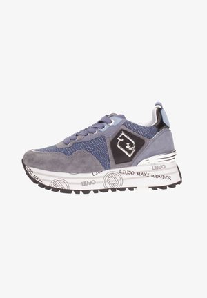 Grijze en blauwe sneaker met suède en stoffen panelen, decoratief logo aan de zijkant, dikke witte zool met zwarte tekst en patronen, en zwarte loopzool.