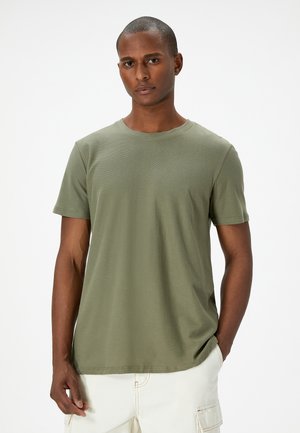 Camiseta de algodón verde oliva con cuello redondo y mangas cortas. Textura suave, corte relajado y dobladillo recto.