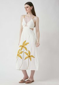 Weißes Leinen-Midikleid mit einem Cutout-Design, das gelbe gestickte Palmenblätter am Saum aufweist. Dünne Träger und ein V-Ausschnitt.