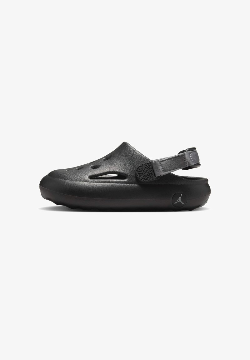 Svart slip-on sandal i gummi med en strukturerad hälrem, ventilationshål och en cirkulär logodetalj på sidan.