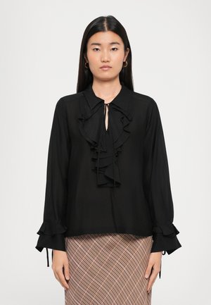 Black blouse with a ruffled front, tie collar, and long sleeves featuring ruffle accents at cuffs. Made from lightweight fabric.