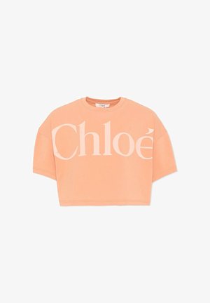 T-shirt court couleur pêche avec grand logo "Chloé" rose pâle sur le devant et col rond.