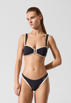 Črni bikini komplet z bandeau zgornjim delom s sredinsko zaponko, belim robom in ujemajočim visokim pasom z obrobami na straneh.