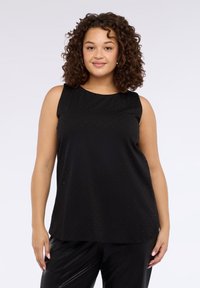 Czarny top bez rękawów z okrągłym dekoltem, o gładkiej fakturze i subtelnym, kropkowanym wzorze na całej powierzchni. W połączeniu z błyszczącymi czarnymi spodniami.