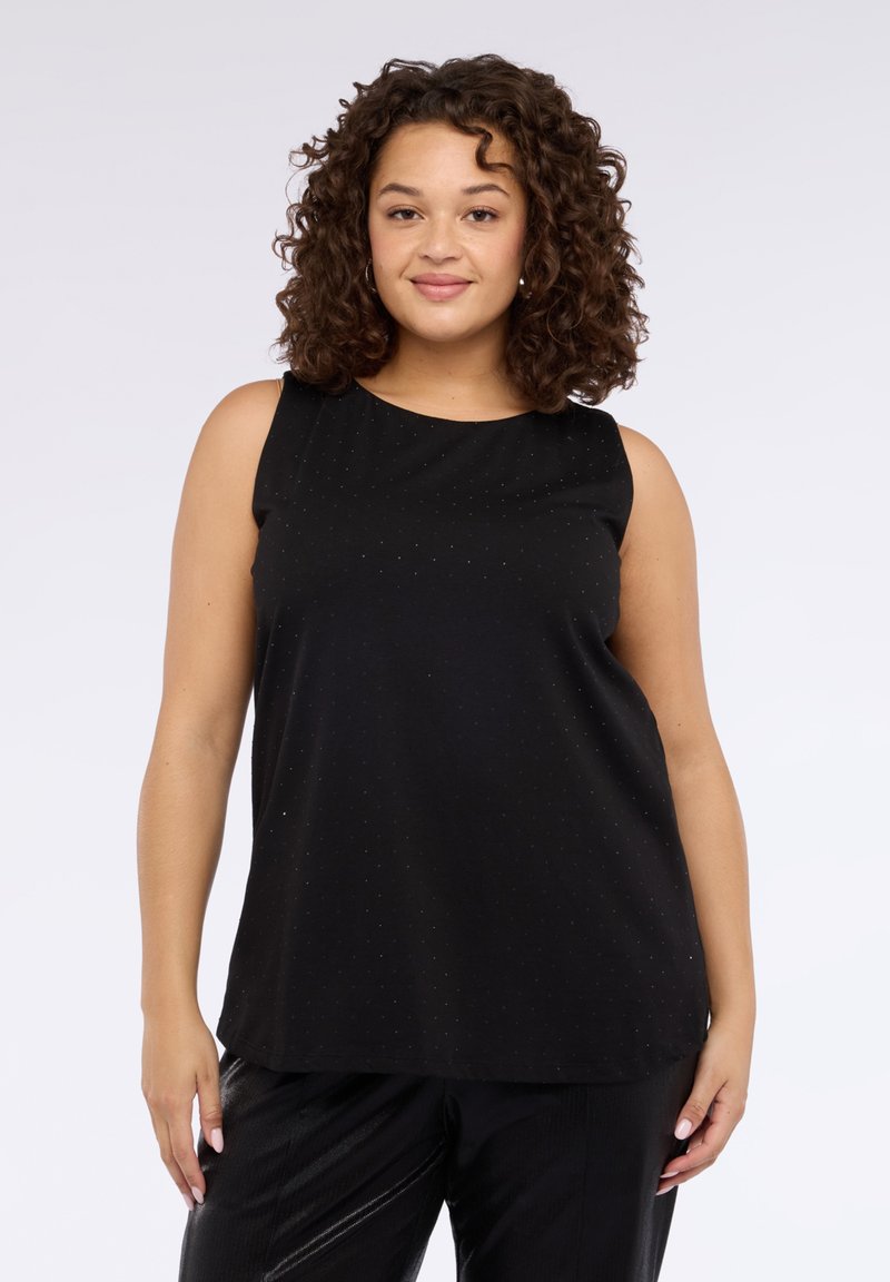 Czarny top bez rękawów z okrągłym dekoltem, o gładkiej fakturze i subtelnym, kropkowanym wzorze na całej powierzchni. W połączeniu z błyszczącymi czarnymi spodniami.
