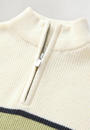 Kraagloze, crèmekleurige pullover met ribbelstructuur en een halve rits. De ondersectie heeft horizontale strepen in olijfgroen en donkergroen.