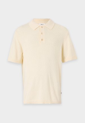 Kort krämfärgad polo med en texturerad tyg, klassisk krage och treknapprad. Har kort ärm och ribbade mudd.