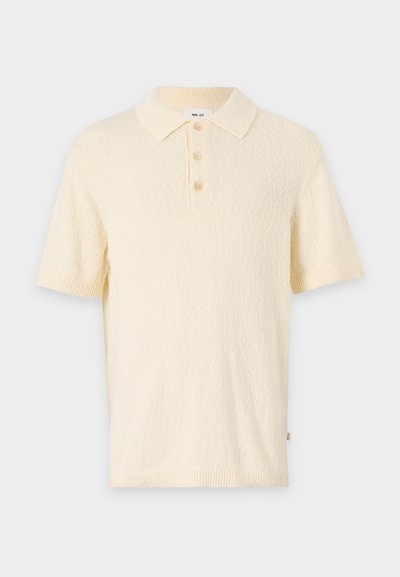 Krótka kremowa koszulka polo z fakturowanej tkaniny, klasycznym kołnierzykiem i trzyguzikowym zapięciem. Posiada krótkie rękawy oraz ściśnięte mankiety.