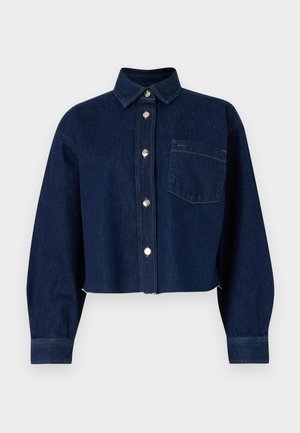 Veste cropped en denim bleu foncé avec fermeture à boutons, col pointu, manches longues et une poche avant. Comprend des boutons métalliques et des accents de couture.