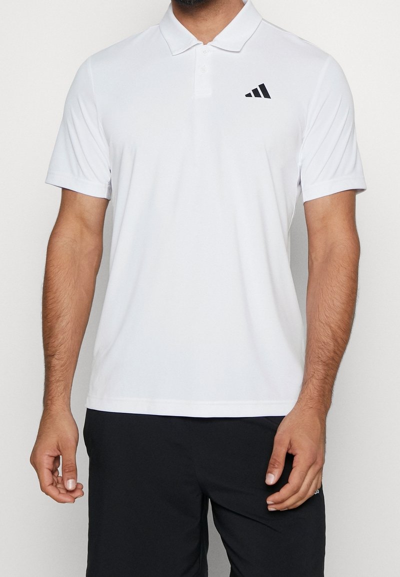 Polo blanc en tissu respirant, avec un col classique et des manches courtes. Comprend un logo Adidas noir sur la poitrine gauche.