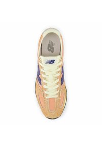 La scarpa presenta una tomaia in pelle scamosciata texturizzata color pesca e viola, lacci color crema e una suola bianca. Logo visibile sulla linguetta e nella soletta.