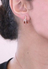 Ohrringe aus roségold mit strukturiertem Design, versehen mit kleinen funkelnden Akzenten entlang des Randes, präsentiert an einem Ohr.