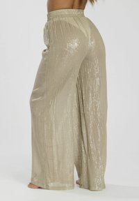 Lichtbeige wijde broek met een gestructureerde, glanzende afwerking, voorzien van een geraffineerde elastische tailleband en lange, vloeiende benen.