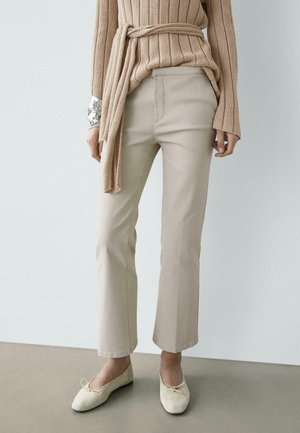 Pantalon beige à jambes droites associé à un pull côtelé beige noué à la taille et des ballerines beige clair.