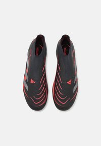 Sorte sportsko med røde detaljer og grå striber. Slankt design med en tekstureret overdel og slip-on stil. Ingen synlige snørebånd.
