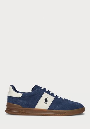 Sneaker in pelle scamosciata blu navy con pannello laterale bianco e lacci, suola marrone e logo Polo sul lato e sul tallone.
