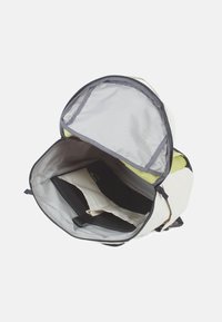 Rugzak met een witte stoffen buitenkant, grijze rits en een ruime binnenkant met zwarte en crèmekleurige opbergvakken.