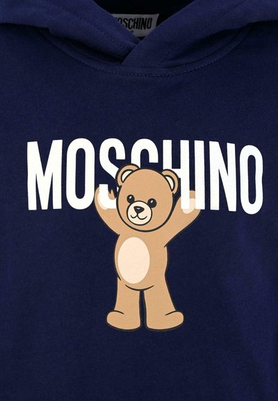 Felpa blu marina con grafica di un orsetto di peluche beige con le braccia sollevate e il testo "MOSCHINO" sopra in lettere bianche in grassetto. Materiale in cotone liscio.