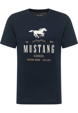 Sötétkék, rövid ujjú pamut póló. Fehér ló grafikával és bézs szöveggel rendelkezik: "MUSTANG CLASSICS" és "ESTD 1932".