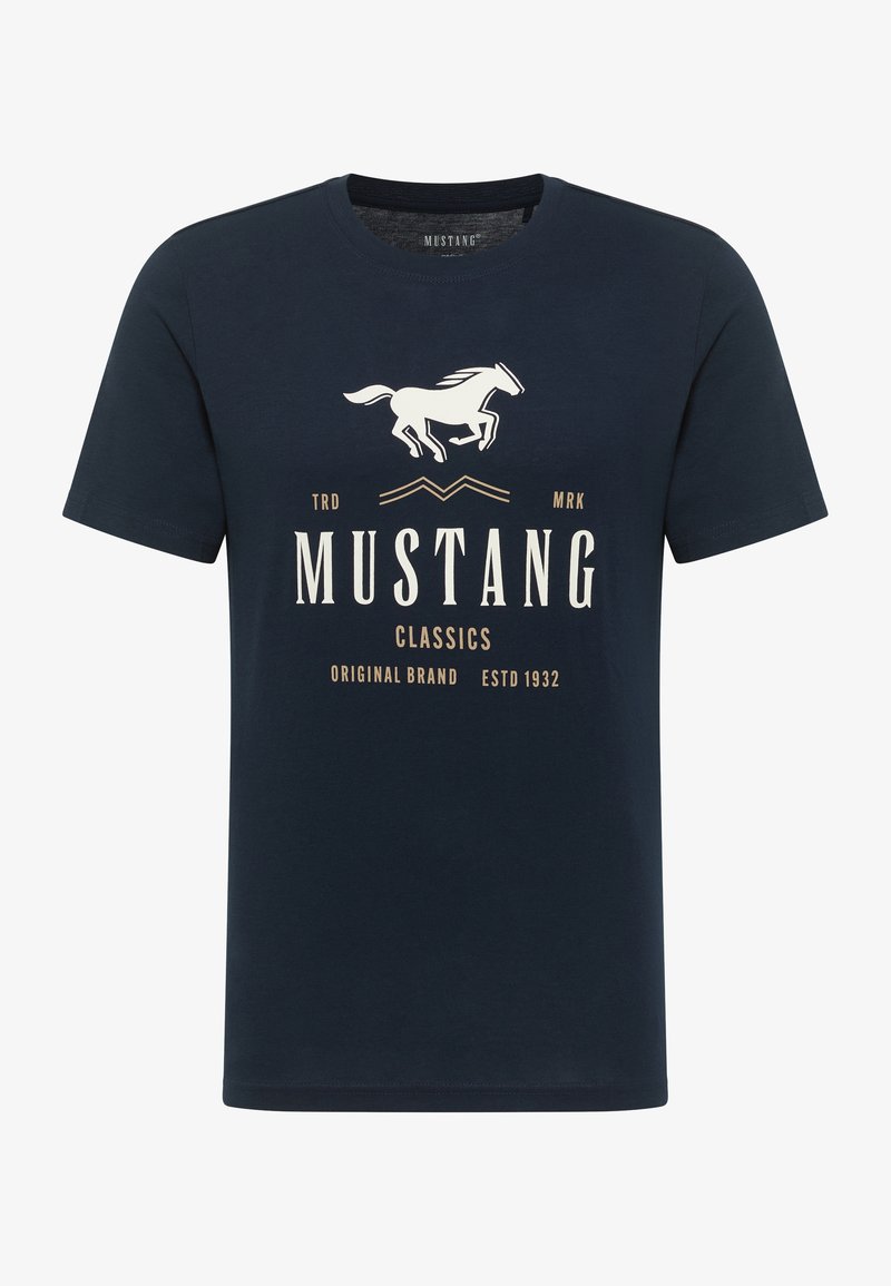 Tamsiai mėlyna trumpomis rankovėmis marškinėliai, pagaminti iš medvilnės. Sukurtas su balta arklio grafika ir smėlio spalvos tekstu: "MUSTANG CLASSICS" ir "ESTD 1932".