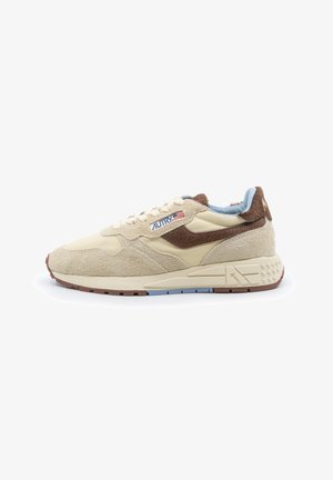 Beiger und brauner Sneaker aus Wildleder und Stoff mit blauem Innenfutter, Logo und amerikanischer Flagge an der Seite sowie strukturierter Sohle.