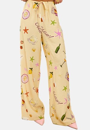 Pantalons larges beige clair avec un imprimé ludique d'éléments alimentaires, de boissons et d'étoiles de mer. Le tissu semble doux avec une taille à cordon.