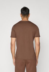 Brun, kort�ærmet t-shirt lavet af blødt materiale, med rund hals og en afslappet pasform. Synlige sømme og ingen fremtrædende mønstre.