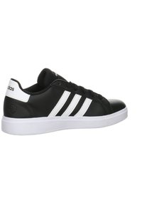 Czarne syntetyczne sneakersy z białymi paskami i akcentami. Charakteryzują się gładką teksturą, okrągłym noskiem, płaską białą podeszwą i sznurowanym zapięciem.