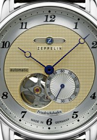 Automatische Zeppelin-Uhr mit einem strukturierten goldenen Zifferblatt, blauen Zeigern, silbernen Akzenten und sichtbarem Uhrwerk. Gehäuse in Deutschland gefertigt.