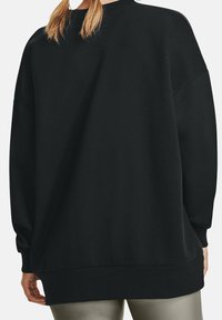 Sudadera negra de gran tamaño con un cuello y puños acanalados. Textura suave, mangas largas y un corte relajado. Dobladillo reforzado en la parte inferior.