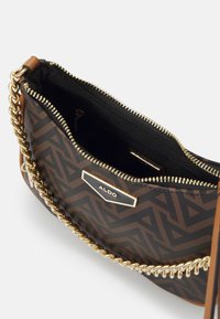 Braune Handtasche mit Muster, Kettenriemen, goldfarbenem Reißverschluss und schwarer Innenauskleidung. Verfügt über ein markiertes Schild und eine Reißverschlusstasche im Inneren.