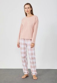 Ροζ ανοιχτόχρωμο μακρυμάνικο τοπ συνδυασμένο με λευκό και ροζ καρό παντελόνι πιτζάμας. Μαλακό ύφασμα, άνετη εφαρμογή, λάστιχο στη μέση του παντελονιού.