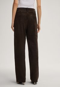 Braune Wildleder-Hosen mit weitem Bein und hoher Taille, ausgestattet mit Gesäßtaschen und sauberen Nähten für ein elegantes Finish. Entworfen für eine lässige Passform.