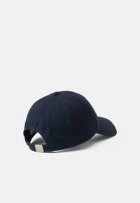 Gorra de béisbol azul marino hecha de algodón, con visera curva, correa ajustable en la parte posterior y sutiles acentos de costura.