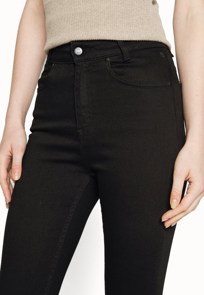 Jeans de denim pretos com um design ajustado, detalhe em botão prateado e bolsos frontais. O tecido tem uma textura suave com detalhes mínimos.