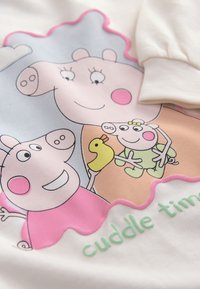 White fabric features a colorful cartoon print of three pigs with a yellow duckling, framed by pink and orange accents, labeled "cuddle time."