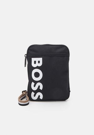 Lille sort pung med lynlås og beige, hvid og sort håndledsrem, med stor hvid lodret tekst med ordet BOSS på forsiden.