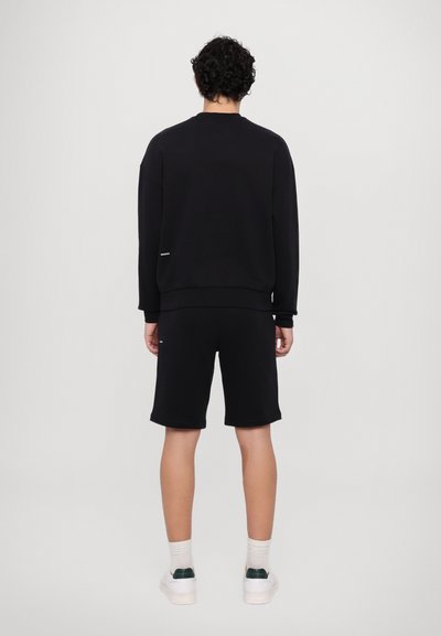 Schwarzer Sweatshirt mit Rundhalsausschnitt, gerippten Bündchen und passenden schwarzen Shorts. Beide Kleidungsstücke bestehen aus einem weichen Material.
