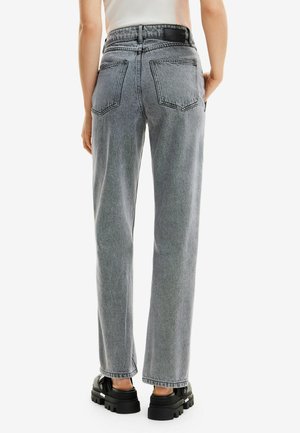 Jeansy z wysokim stanem i prostymi nogawkami w jasnoszarym deniowym materiale. Posiadają kieszenie naszywane, widoczne szwy oraz lekko wyblakłą teksturę.