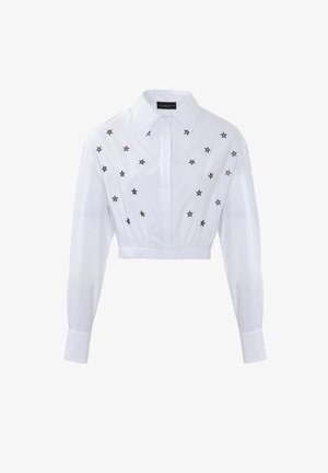 Witte cropped shirt met lange mouwen, voorzien van zwart sterrenborduurwerk aan de voorkant. Elastische tailleband en klassiek kraagontwerp.