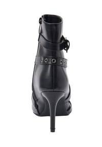 Zwarte stiletto enkelboot met zijrits, decoratieve riem met metalen oogjes en gespdetail rond de enkel.