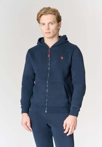 Felpa con cappuccio blu navy con cerniera, realizzata in tessuto morbido, con una cerniera con accento rosso e un piccolo logo ricamato sul petto.