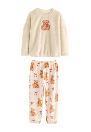 Kremowy, puszysty top z długim rękawem z misiem na piersi oraz pasujące kremowe spodnie z wzorami misiów i różowych kokardek.