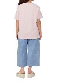 Roze katoenen t-shirt met een ontspannen pasvorm, gecombineerd met vervaagde blauwe wijde broekspijpen en beige platform sandalen. Eenvoudig ontwerp, casual stijl.