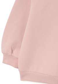 Las mangas de la sudadera rosa cuentan con puños de canalé y una tela suave y texturizada. Costuras limpias con un acabado suave. Sin patrones ni acentos visibles.