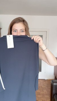 Navyblaues Oberteil mit glatter Textur, das einen weißen Akzent am Ausschnitt hat. Etikett oben links sichtbar. Rechteckige Form.