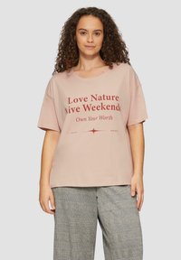 Lichtroze katoenen t-shirt met korte mouwen, voorzien van een gedurfde rode grafische tekstontwerp. Casual pasvorm en ronde halslijn.